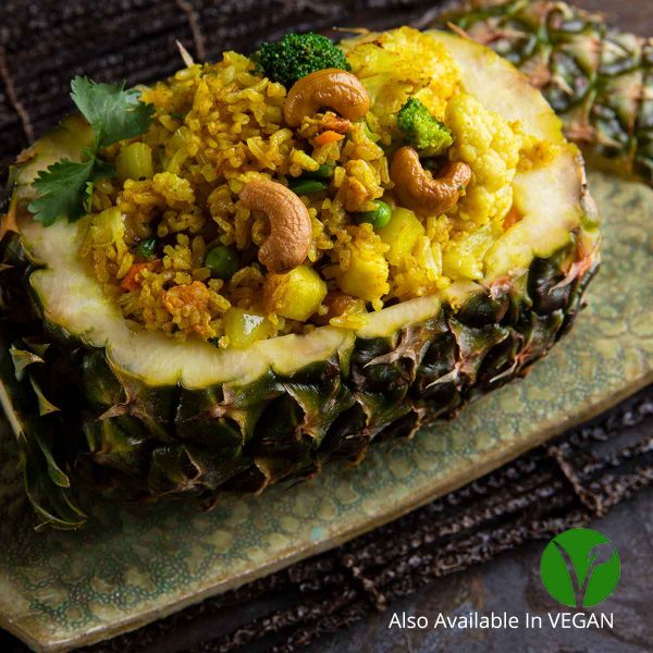 Pineapple fried rice with mixed vegetables, eggs, raisins & cashew nuts served in a pineapple shell